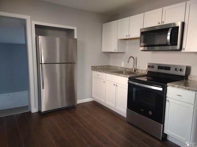 113 Walnut St, Brooklyn, MI 49230 - kitchen with stainless steel appliances, a sink, dark wood-style floors, white cabinets, and baseboards
