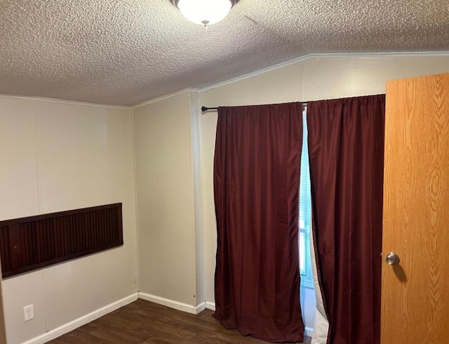 empty room with a textured ceiling, lofted ceiling, and dark wood-type flooring