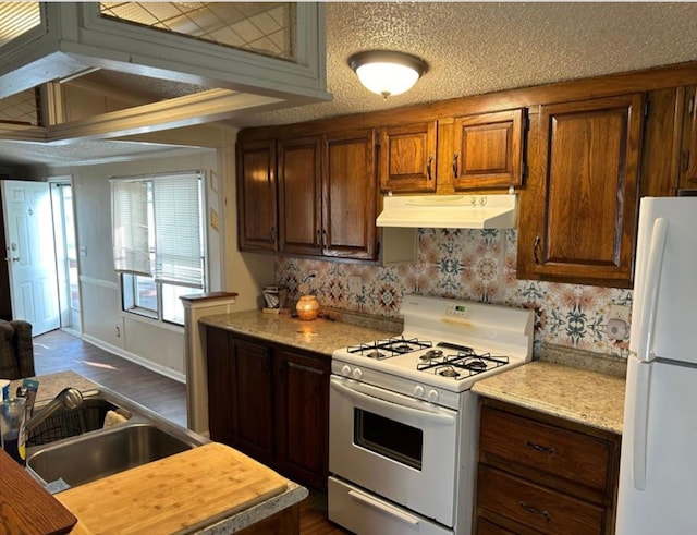 kitchen with a textured ceiling, dark hardwood / wood-style flooring, white appliances, and sink