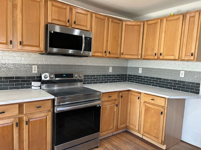 kitchen with decorative backsplash, appliances with stainless steel finishes, and dark hardwood / wood-style flooring