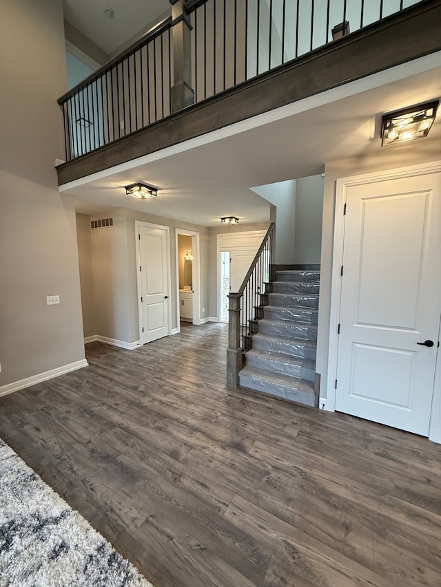 stairs with wood-type flooring and a towering ceiling