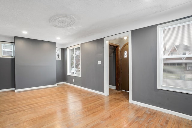 empty room with light hardwood / wood-style floors and a textured ceiling