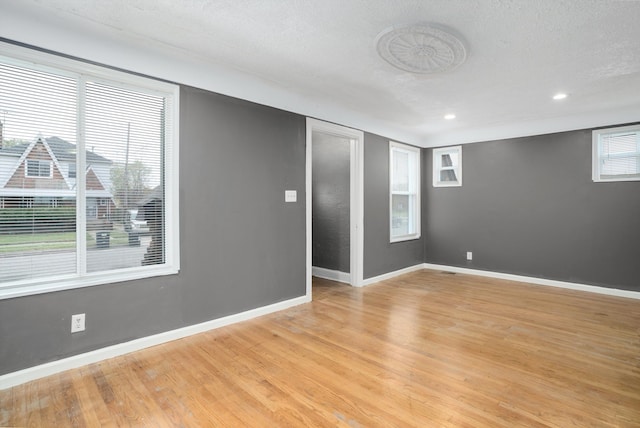 unfurnished room with a textured ceiling, light wood-type flooring, and plenty of natural light