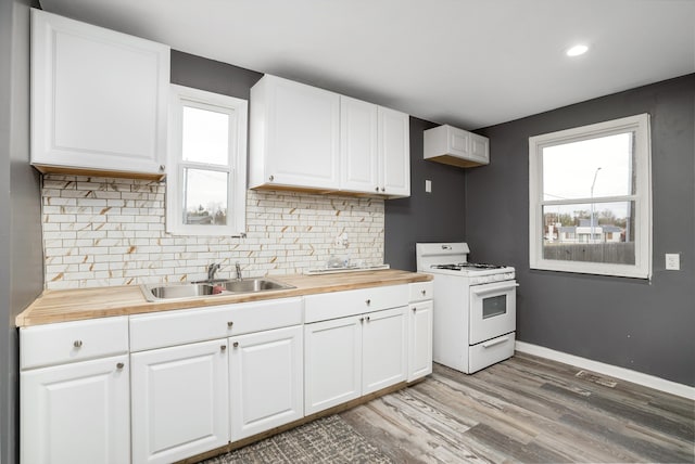 kitchen featuring butcher block countertops, plenty of natural light, white range with gas stovetop, and sink