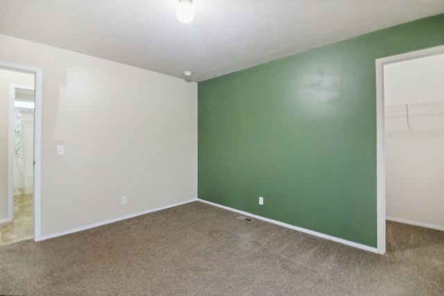 unfurnished bedroom featuring carpet flooring, a walk in closet, and a closet