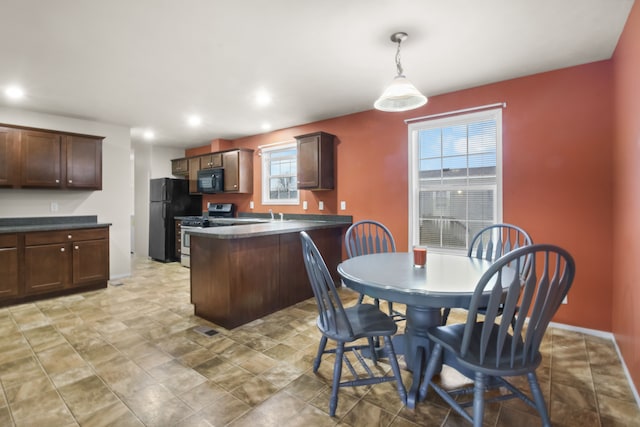 kitchen featuring kitchen peninsula, a breakfast bar, dark brown cabinets, black appliances, and hanging light fixtures