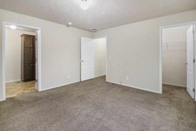 unfurnished bedroom with light carpet, a spacious closet, and a closet