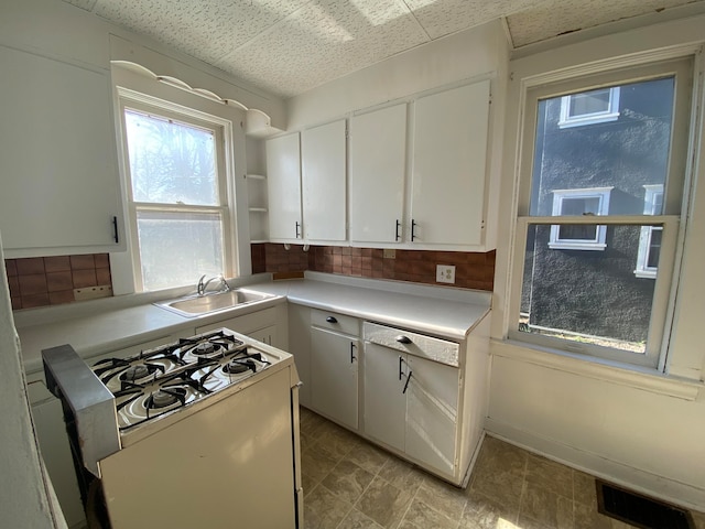 kitchen with decorative backsplash, white cabinetry, sink, and white gas range oven