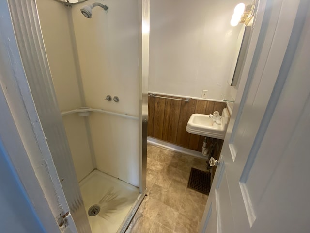 bathroom featuring wood walls, sink, and a shower