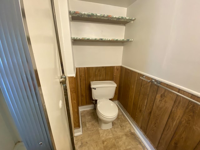 bathroom with wooden walls and toilet