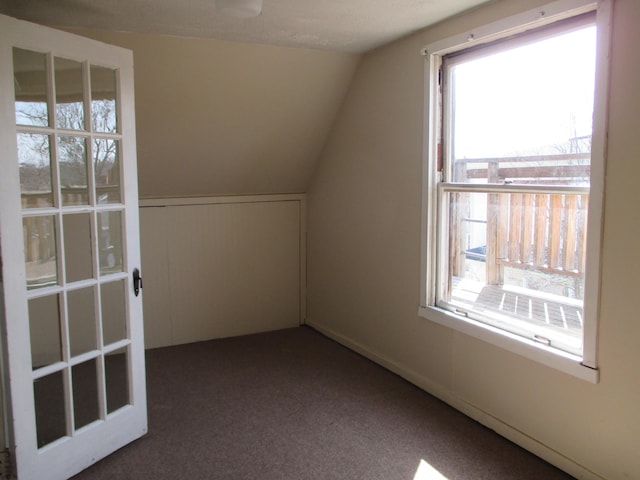 bonus room with dark carpet and vaulted ceiling