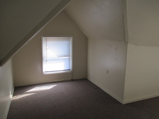 bonus room with dark colored carpet and vaulted ceiling