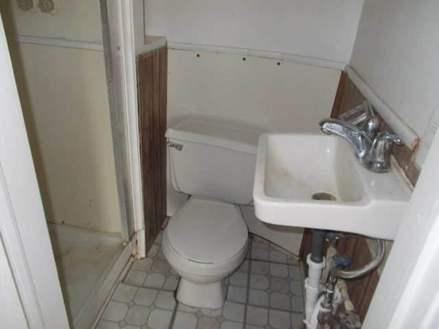 bathroom with walk in shower, sink, tile patterned flooring, and toilet