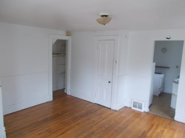 unfurnished bedroom with connected bathroom and dark wood-type flooring