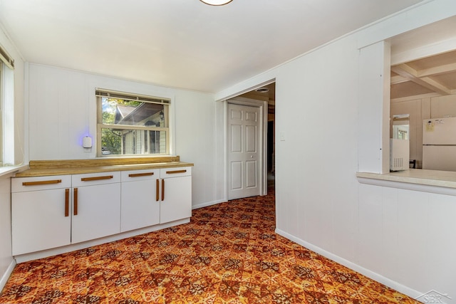 interior space with white refrigerator and white cabinetry