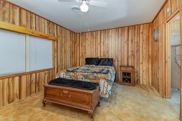 bedroom with light carpet, ornamental molding, ceiling fan, and wooden walls