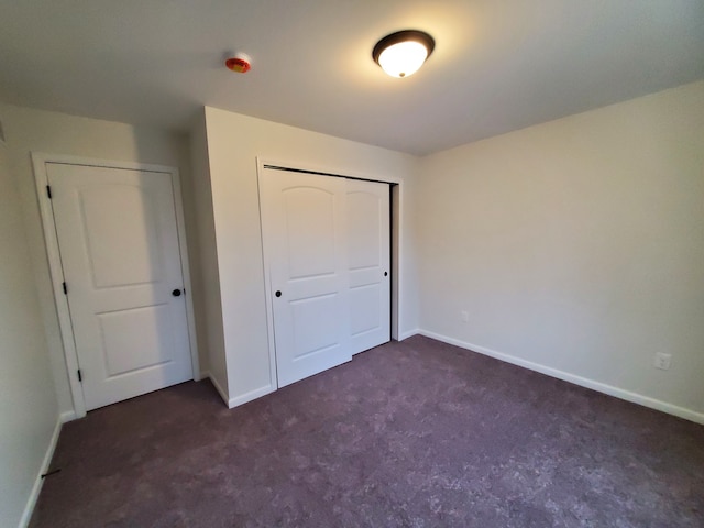 unfurnished bedroom featuring dark colored carpet and a closet