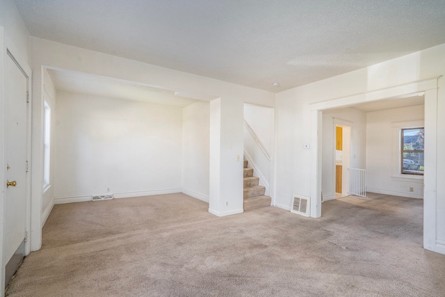 unfurnished room featuring a textured ceiling and light carpet