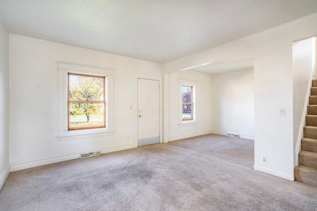 carpeted spare room featuring a textured ceiling