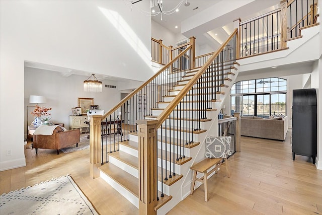 stairs featuring hardwood / wood-style flooring, a towering ceiling, and an inviting chandelier