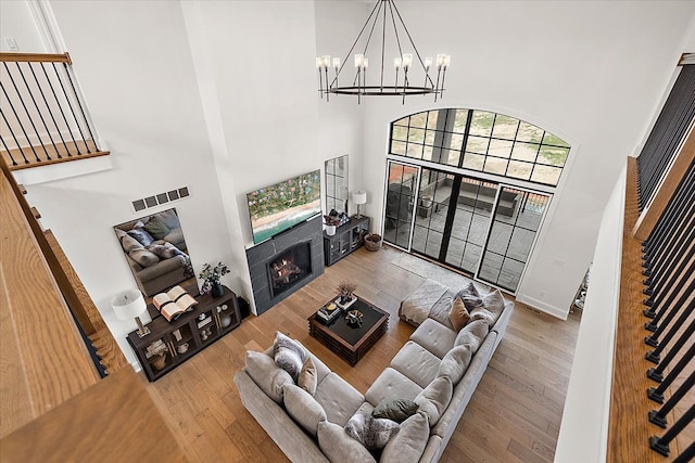 living room featuring hardwood / wood-style flooring, a towering ceiling, and a fireplace