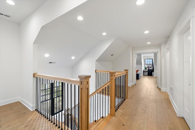 corridor with a wealth of natural light, light hardwood / wood-style flooring, and vaulted ceiling