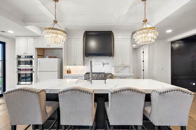 kitchen featuring light hardwood / wood-style floors, white refrigerator, white cabinetry, and a kitchen island with sink