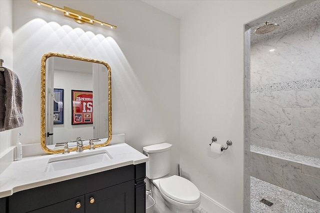 bathroom featuring a tile shower, vanity, and toilet