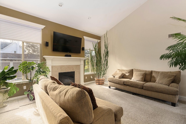 carpeted living room with a tile fireplace and vaulted ceiling