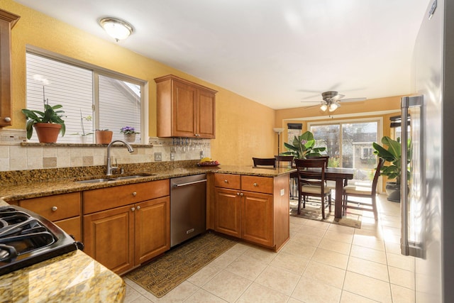 kitchen with stone counters, sink, appliances with stainless steel finishes, tasteful backsplash, and kitchen peninsula