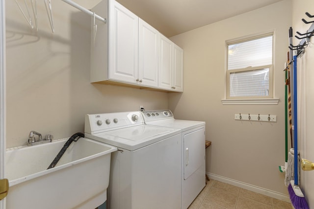 washroom featuring washing machine and dryer, sink, light tile patterned floors, and cabinets