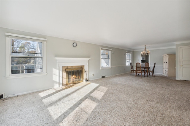 unfurnished living room featuring carpet flooring, plenty of natural light, an inviting chandelier, and a brick fireplace