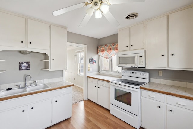 kitchen featuring sink, tile countertops, white appliances, white cabinets, and light wood-type flooring