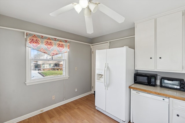 kitchen with tile countertops, white appliances, white cabinets, light hardwood / wood-style flooring, and ceiling fan