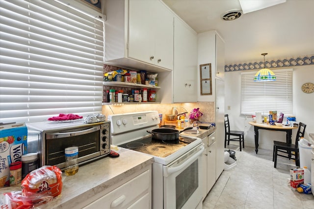 kitchen featuring white cabinets, light tile patterned floors, decorative light fixtures, and white electric stove