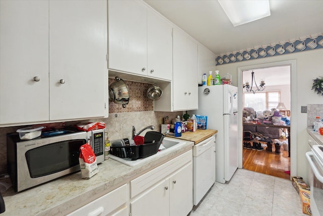 kitchen featuring light wood-type flooring, white appliances, sink, a notable chandelier, and white cabinets