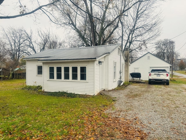 view of side of home featuring a garage, a lawn, and an outdoor structure