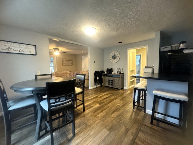 dining space with ceiling fan, dark wood-type flooring, and a textured ceiling