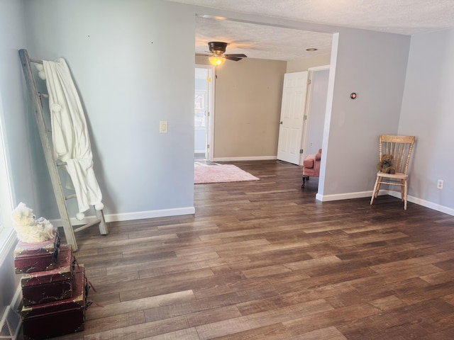 empty room featuring ceiling fan, dark wood-type flooring, and a textured ceiling