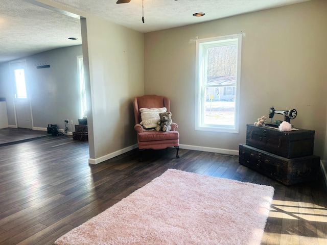 living area with dark hardwood / wood-style flooring, ceiling fan, and a textured ceiling