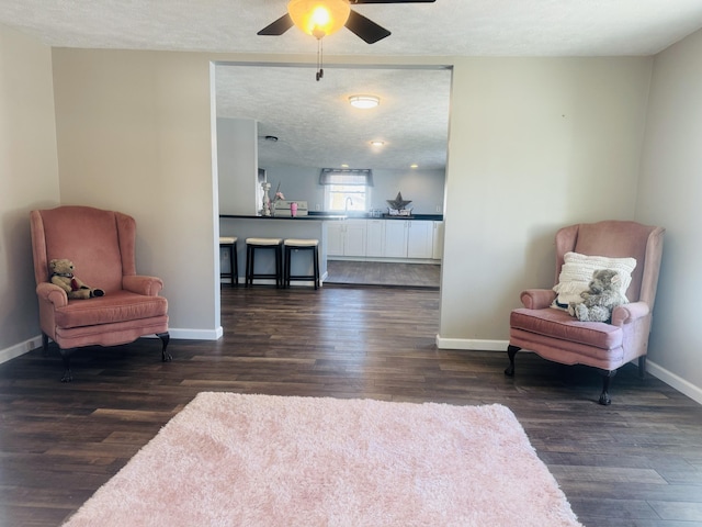 sitting room featuring ceiling fan, dark wood-type flooring, and a textured ceiling