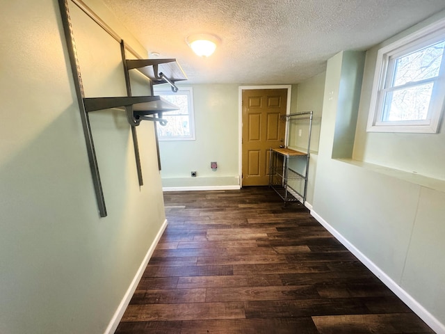 corridor featuring a wealth of natural light, dark hardwood / wood-style floors, and a textured ceiling