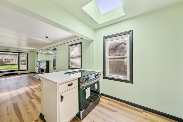 kitchen featuring a skylight, pendant lighting, white cabinets, light hardwood / wood-style floors, and black / electric stove