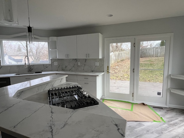 kitchen with light stone counters, white cabinets, and a healthy amount of sunlight