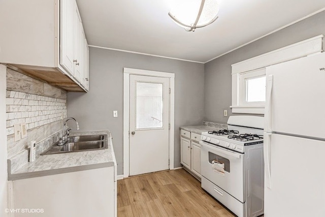 kitchen with white cabinetry, sink, backsplash, light hardwood / wood-style floors, and white appliances