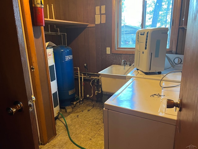 laundry room featuring sink, wood walls, and washing machine and clothes dryer