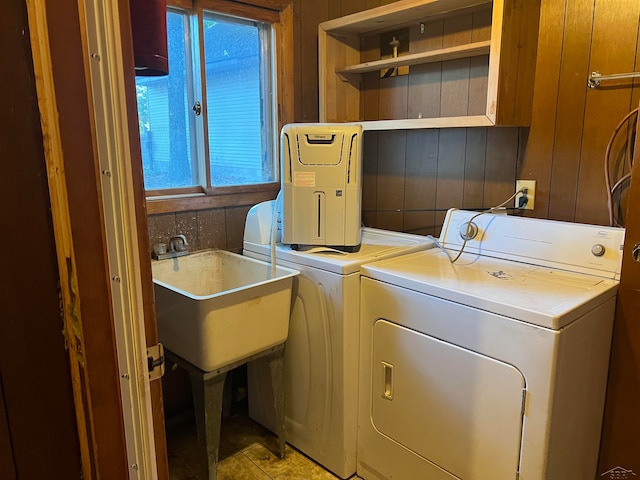 washroom with wooden walls, washer and clothes dryer, and sink