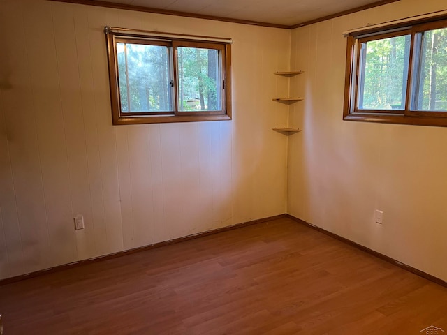 unfurnished room with wooden walls, light hardwood / wood-style flooring, and ornamental molding