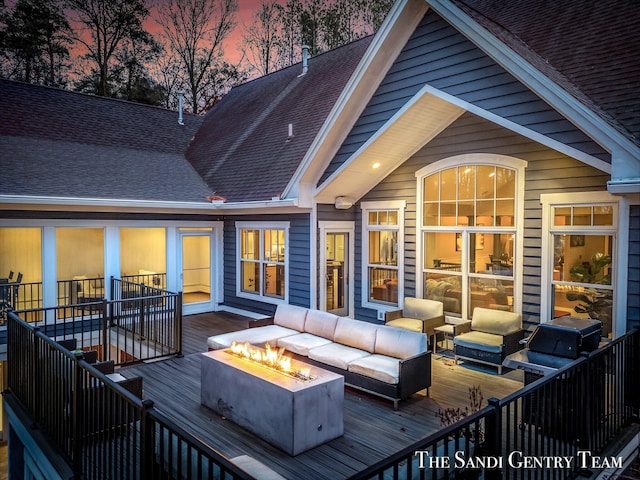 deck at dusk featuring an outdoor living space with a fire pit