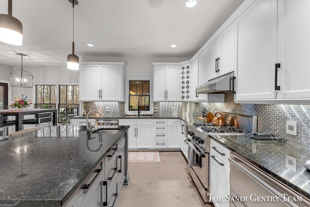 kitchen with pendant lighting, stainless steel range, dark stone counters, and sink